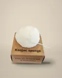 Éponge konjac blanche posée sur sa nouvelle boîte en carton kraft