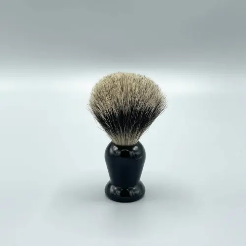Brocha de afeitar Best badger con mango negro brillante y pelos bicolores sobre fondo gris