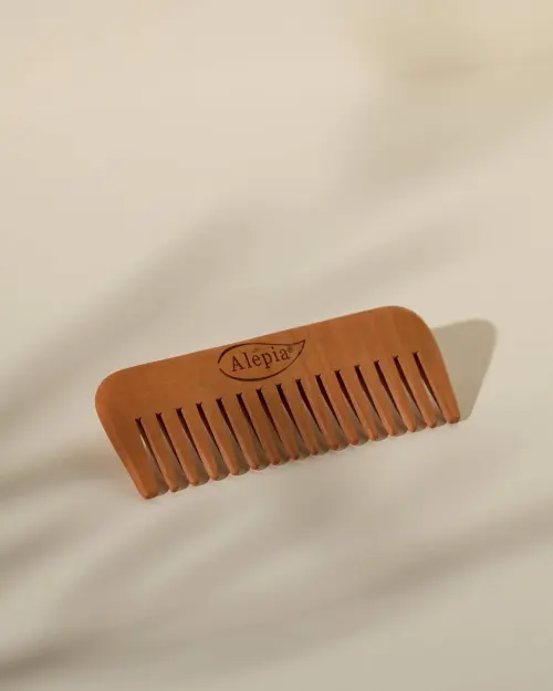 Ontwarmende kam van perenhout van Alepia met brede tanden, op een strakke beige achtergrond