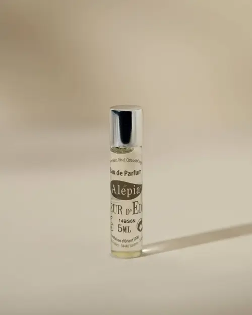 Roll-on Fleur d'Eden Alepia en frasco de vidrio de 5 ml con tapón plateado sobre fondo beige