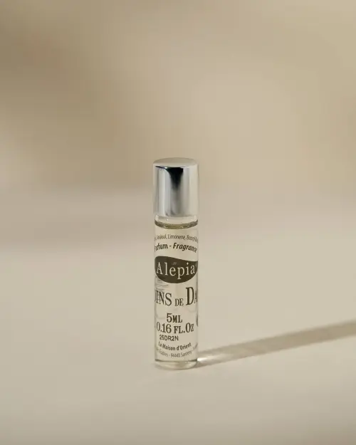 Roll-on Les Jardins de Damas Alepia de 5 ml en frasco transparente con tapón plateado sobre fondo beige