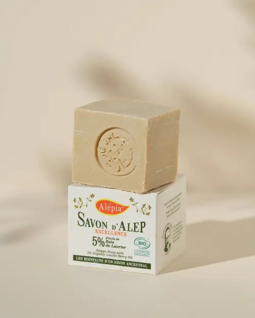 Sapone di Aleppo Excellence 5% alloro Alepia, panetto cubico stampigliato posato sul suo astuccio in cartone
