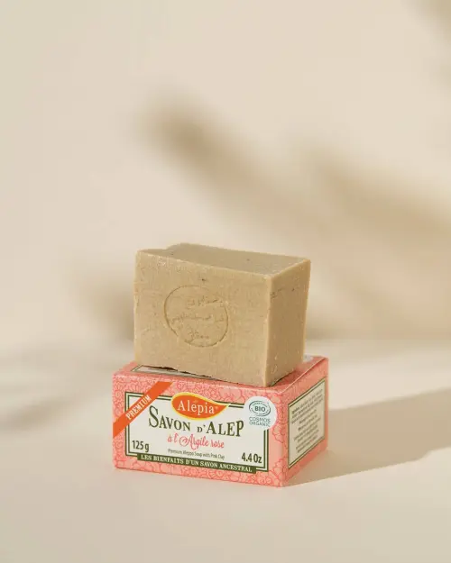 Sapone di Aleppo Premium all'Argilla Rosa Alepia stampigliato, posato sulla sua scatola da 125 g