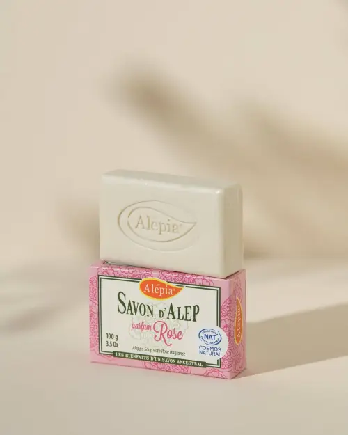 Sapone di Aleppo Prestige alla Rosa Alepia, panetto bianco inciso posato sulla sua confezione rosa da 100 g