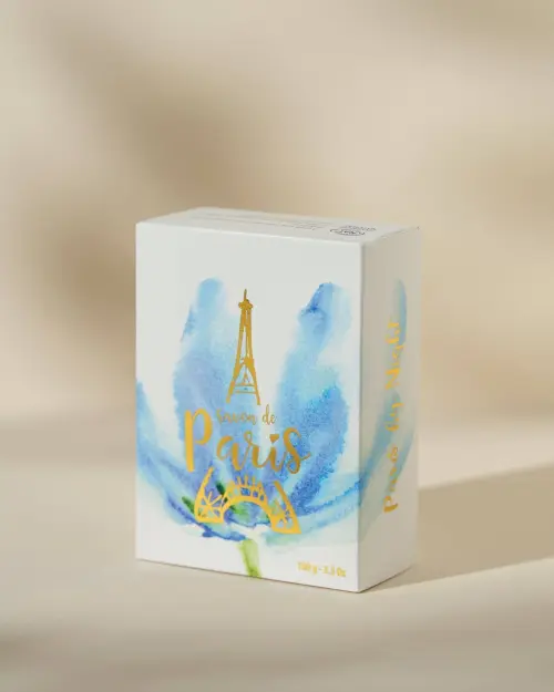 Jabón de París Paris By Night en su estuche blanco adornado con una flor azul y una torre Eiffel dorada