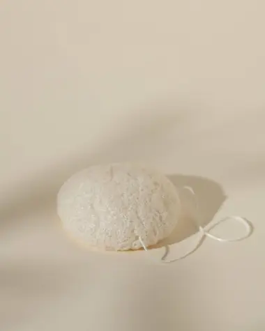 Esponja konjac blanca en forma de cúpula con textura porosa y su cordón blanco