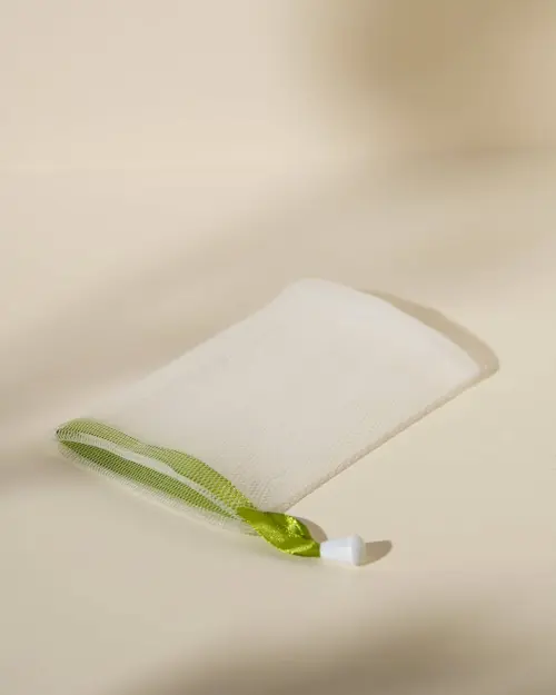 Rete schiumogena bianca in maglia fine con cordino verde posata piatta su fondo chiaro