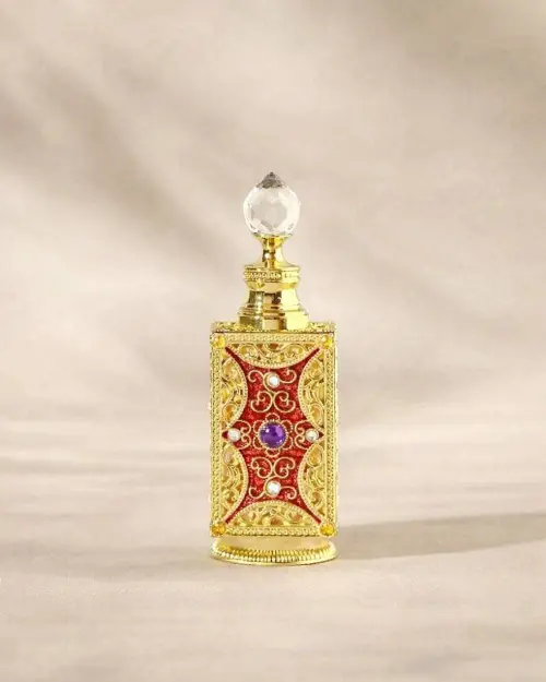 Flacone di profumo dorato ornato di motivi rossi, di strass e di un tappo in cristallo tagliato